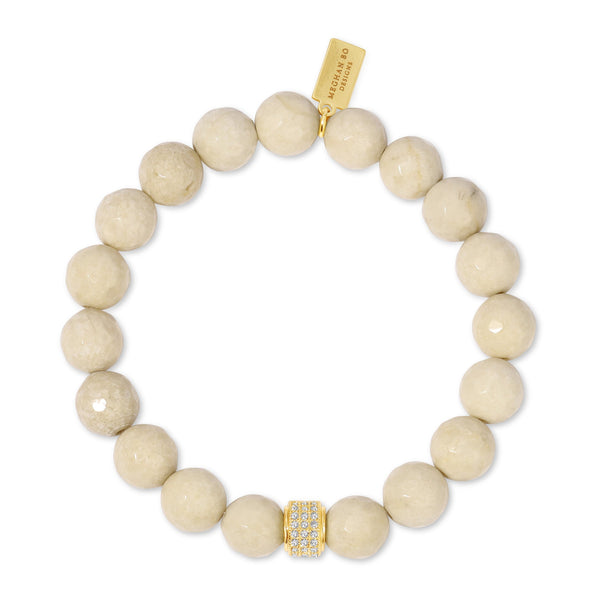Natural Fossil Stone Beaded Stretch Bracelet | Meghan Bo featuring polished beige fossil stone beads with a gold-tone crystal-encrusted accent bead and a branded gold tag for a chic wellness accessory.