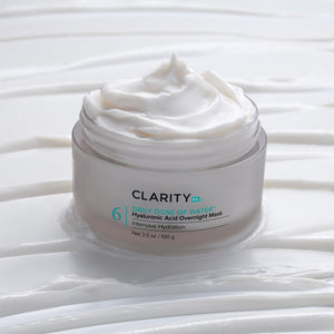 Open jar of creamy white skincare product labeled Daily Dose of Water™ Hyaluronic Acid Overnight Mask | ClarityRx, placed on textured white surface with smooth cream swirls.