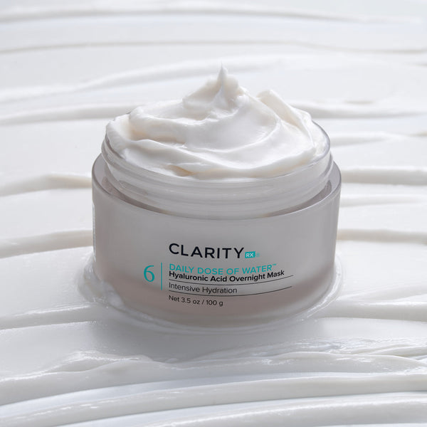 Open jar of creamy white skincare product labeled Daily Dose of Water™ Hyaluronic Acid Overnight Mask | ClarityRx, placed on textured white surface with smooth cream swirls.