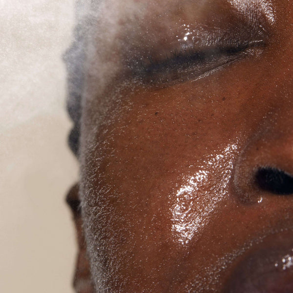 Close-up of a person with dewy skin and closed eyes as they spray Queen of Hungary Mist | Omorovicza, highlighting a refreshing moment of skincare and hydration.