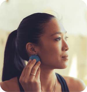 Woman using a blue RAD Rounds - 3 Set | RAD massage tool on her jawline for skincare and muscle recovery in a wellness routine.