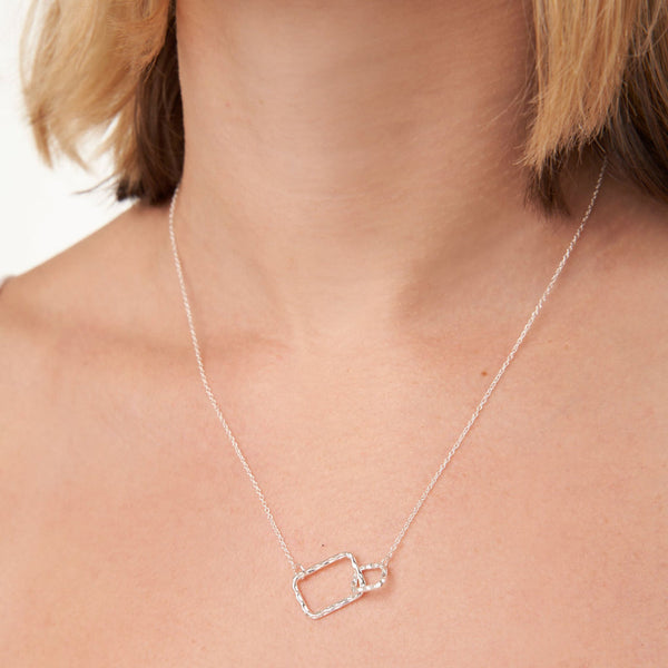 Close-up of a woman wearing a delicate silver chain featuring two interlinked rectangular pendants showcasing the Geometry Rectangles Necklace | Little Sparkles.