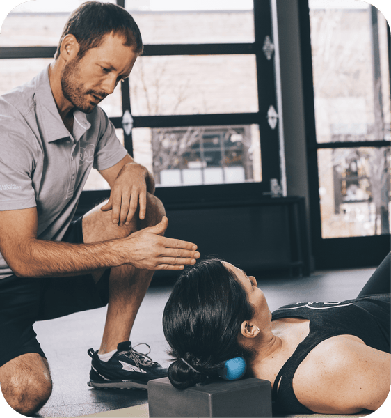 A man guides a woman using the RAD Roller Original | RAD under her neck for targeted muscle recovery and relief in a wellness setting.