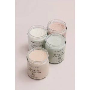 Four glass jars of French Girl skincare polishes in soft pastel colors, including Rose Body Polish | French Girl, arranged on a pale background for body care and wellness.