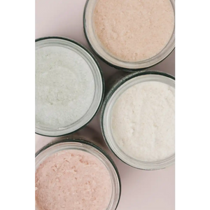 Close-up of four glass jars filled with textured natural body scrubs in soft pastel shades, featuring Rose Body Polish | French Girl for skincare and body care.