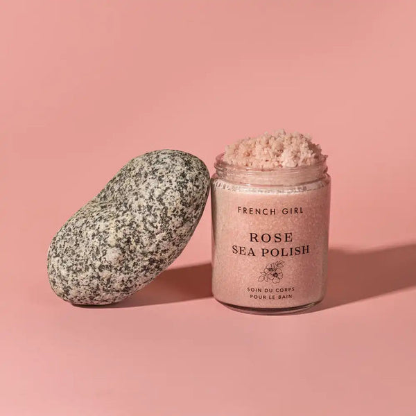 Jar of Rose Body Polish | French Girl with pink exfoliating scrub next to a smooth speckled stone on a soft pink background, showcasing natural skincare and body care.