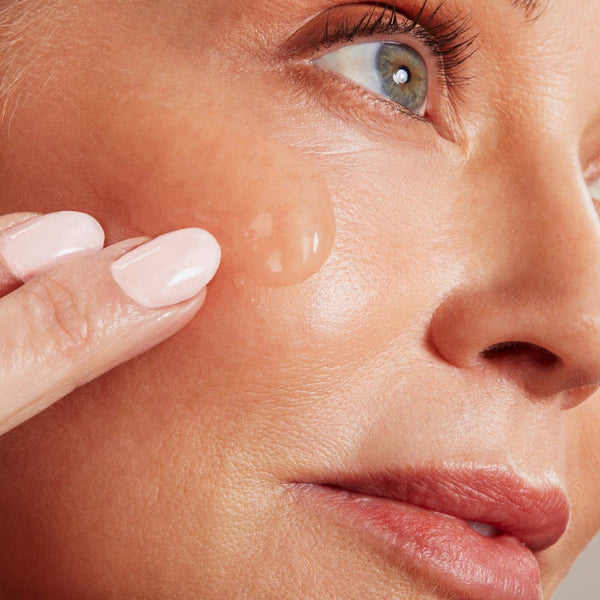 Close-up of a woman applying Hydrating Aqua Gel | NuFACE to her cheek, highlighting smooth skin and skincare routine for hydration and wellness.