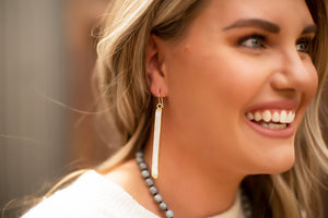 Close-up of a smiling woman wearing long white selenite crystal earrings with gold accents, showcasing Selenite Earrings | Meghan Bo in a natural light setting.