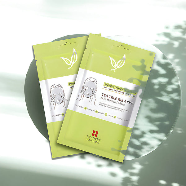 Two green packets of Tea Tree Relaxing Skin Renewal Mask | Leaders displayed on a round surface with soft shadows, highlighting skincare and wellness themes.