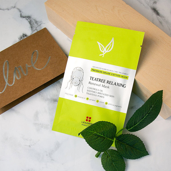 Packaging of Tea Tree Relaxing Skin Renewal Mask | Leaders placed on a marble surface next to a brown card with the word love and fresh green leaves, showcasing a fresh and natural skincare product.
