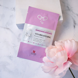 Vita Brightening Skin Renewal Mask | Leaders in purple packaging on a white marble surface next to a soft pink flower, promoting skincare and skin brightening benefits.