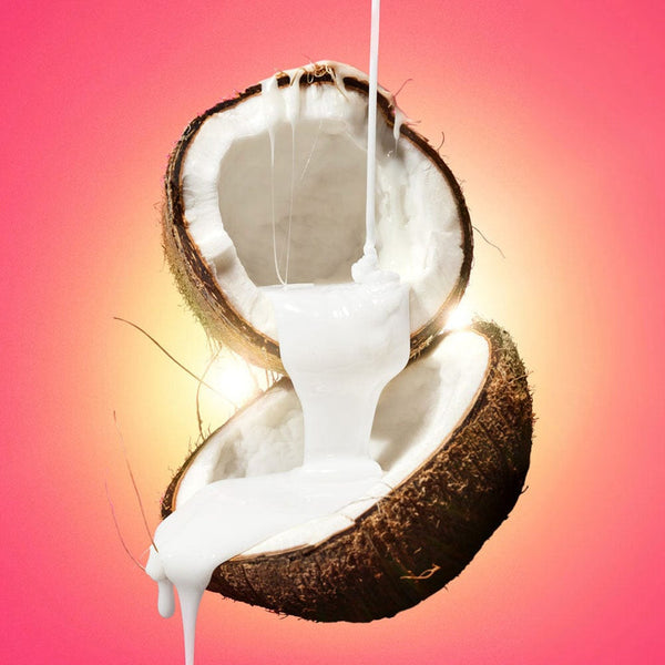 Creamy white wax pouring into an open coconut against a vibrant pink background, showcasing I'm Sensitive Meltdown Vegan Hard Wax | Crybaby Wax for skincare and body care.
