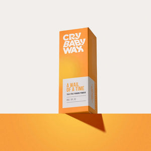 Orange and white packaging of A Wail of a Time Priming Powder | Crybaby Wax displayed on an orange surface with a soft shadow, highlighting skincare wellness.