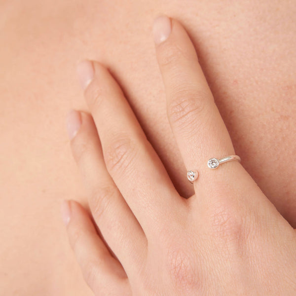 Close-up of a hand wearing a delicate white ring with two small clear stones, showcasing the Jelly Tots Ring | Little Sparkles design.