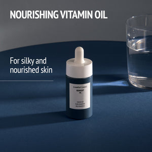 Bottle of Renight Oil | [ comfort zone ] with dropper on a dark surface next to a glass of water, promoting nourishing vitamin oil for silky and nourished skin skincare.