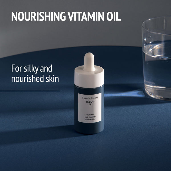 Bottle of Renight Oil | [ comfort zone ] with dropper on a dark surface next to a glass of water, promoting nourishing vitamin oil for silky and nourished skin skincare.