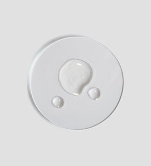 Clear liquid droplets on a white surface showcasing the texture of Tranquillity Oil (Bath & Body) | [ comfort zone ] for skincare and body care wellness.
