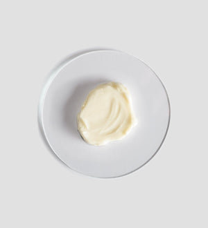 A smooth dollop of moisturizing cream on a white plate, representing the texture of Sacred Nature Hydra Cream | [ comfort zone ] skincare product.