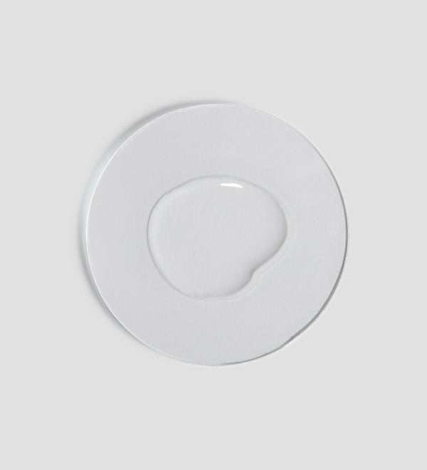 Clear liquid texture of Essential Micellar Water | [ comfort zone ] displayed on a white circular surface, highlighting skincare product clarity and purity.