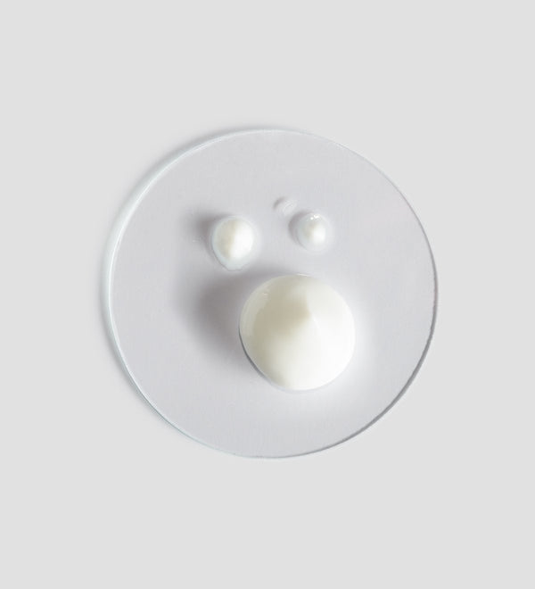 Three different sized dollops of white skincare cream on a clear round dish, representing Essential Peeling | [ comfort zone ] for skincare and wellness.