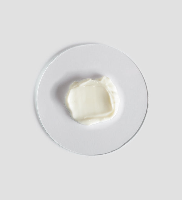 A smooth dollop of creamy white Tranquillity Body Cream | [ comfort zone ] displayed on a clear round surface, highlighting its rich texture for skincare and body care.