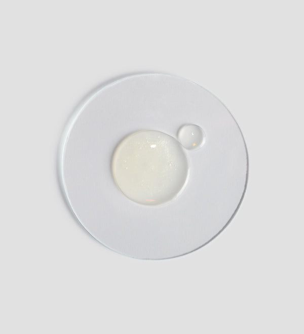 Clear and transparent gel drops on a white surface, representing the texture of Active Pureness Gel | [ comfort zone ] skincare product.