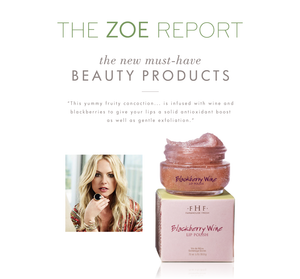 Jar of Blackberry Wine Lip Polish | Farmhouse Fresh with textured lip polish on its lid, next to its pink box packaging, alongside a woman with blonde hair wearing a floral top.