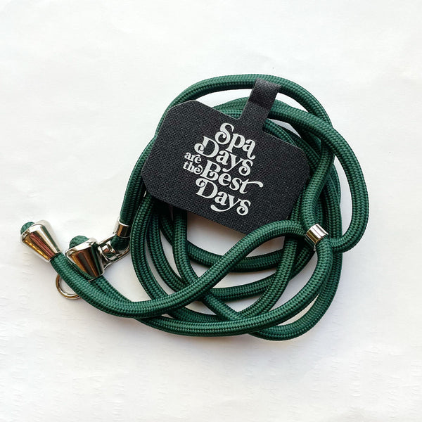 Crossbody Phone Lanyard With Adjustable Strap | Live Love Spa in dark green with silver accents, featuring a tag that says "Spa Days are the Best Days" for skincare and wellness convenience.