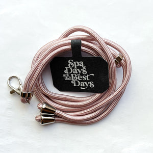 Crossbody Phone Lanyard With Adjustable Strap | Live Love Spa in soft pink with silver-tone metal clasps and a black tag that says "Spa Days are the Best Days" displayed on a white background.