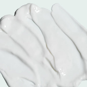 Smooth white creamy texture of ILUMA intense brightening crème | IMAGE Skincare spread on a light background, highlighting its rich skincare formula.