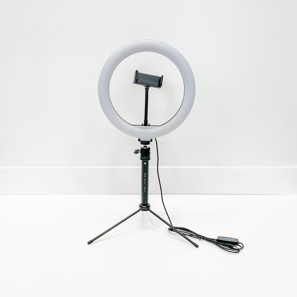 Ring Light - 10" set up on a tripod stand with a phone holder in the center and an attached power cable, against a plain white background.