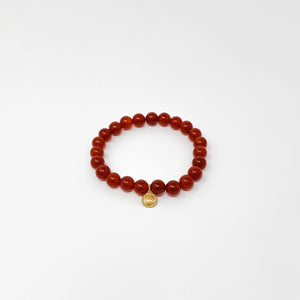 Assorted Satya Bracelets | Satya featuring polished red beads with a small golden charm on a clean white background, reflecting wellness and mindful accessory style.