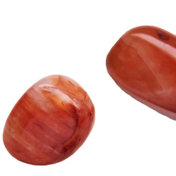 Close-up of smooth reddish-brown polished stones used with the Energy Rollerball | Aluminate Life for wellness and body care routines.
