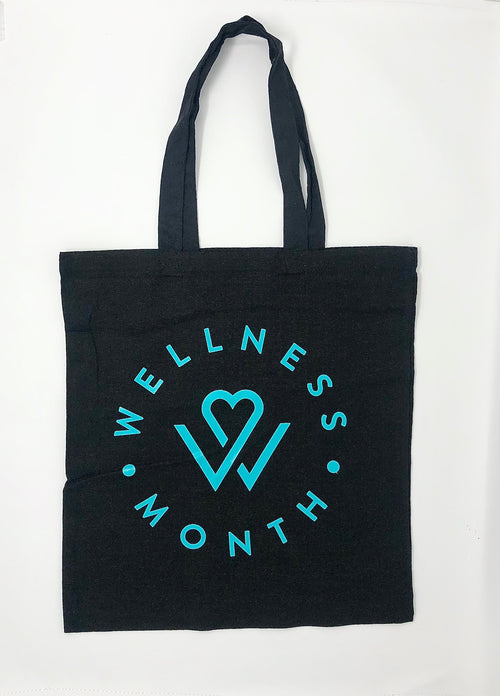 Black tote bag with turquoise circular Wellness Month logo and design, featuring long handles for carrying, showcasing the Wellness Month Tote Bag | Wellness Month.