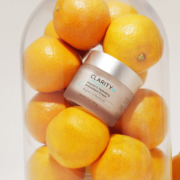 Jar of C-Results™ Vitamin C Hydrating Antioxidant Cream | ClarityRx surrounded by fresh oranges inside a clear glass container, highlighting skincare and natural vitamin C benefits.