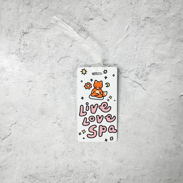 Luggage Tag - Meditating Fox- Limited Edition | Lucky Owl featuring a cute orange fox meditating above the words "Live Love Spa" with stars and celestial designs on a white background.