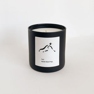 No. 1 Sunrise Island Yoga (Bali) Candle | Lucky Owl in a sleek black glass container with a minimalist white label featuring a simple yoga pose illustration.