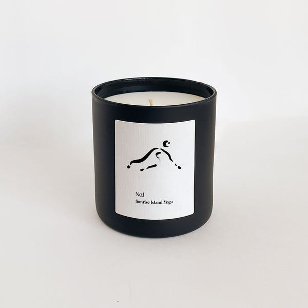 No. 1 Sunrise Island Yoga (Bali) Candle | Lucky Owl in a sleek black glass container with a minimalist white label featuring a simple yoga pose illustration.