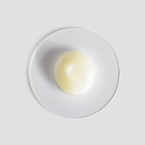Close-up of a smooth, creamy skincare product sample on a white plate showcasing the texture of Essential Face Wash | [ comfort zone ] for gentle daily cleansing.