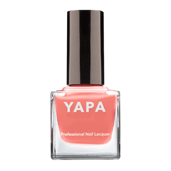 Bottle of coral pink nail polish with black cap labeled Vanessa Nail Lacquer | YAPA, highlighting a smooth, professional finish for manicure care.