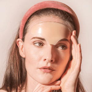 Woman wearing a clear Skin Plumping Reusable Forehead Pad | Dreambox Beauty on her forehead, showcasing a skincare tool designed for hydration and smoothing fine lines.