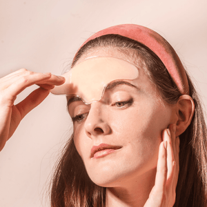 Woman applying a transparent Skin Plumping Reusable Forehead Pad | Dreambox Beauty to her forehead, demonstrating a skincare routine for smooth and hydrated skin.