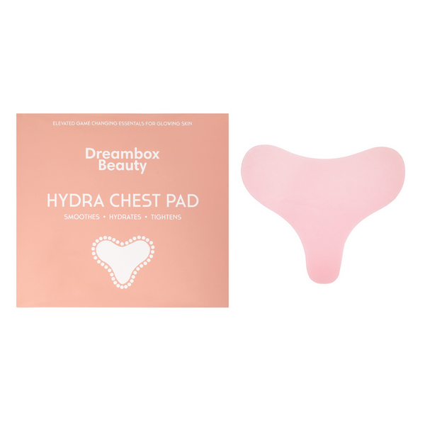 Pink hydrating reusable chest pad with smooth curved design displayed next to peach-colored packaging labeled Dreambox Beauty Hydra Chest Pad promoting skin smoothing, hydration, and tightening benefits, featuring the product title Hydrating Reusable Chest Pad | Dreambox Beauty for wellness and skincare.