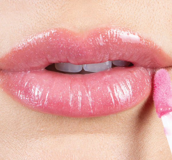 Close-up of lips with glossy, sheer pink shine being applied using a soft applicator featuring Vitamin Glaze® Oil Infused Lip Gloss – Sheer Pink | Farmhouse Fresh.