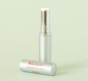 Close-up of an open silver tube of Whoopie® Hydrating Lip Balm | Farmhouse Fresh against a light green background, highlighting its smooth, moisturizing balm stick.