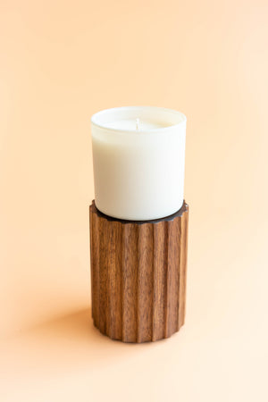 Aspen + Fog Dignity Series Glass Jar Soy Candle | Calyan Wax Co. - 5.3 oz displayed on a textured wooden holder against a soft peach background.