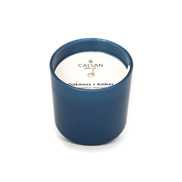 Oakmoss + Amber Dignity Series Glass Jar Soy Candle | Calyan Wax Co. - 5.3 oz in a sleek dark blue glass container with wooden wick and minimalistic label design.
