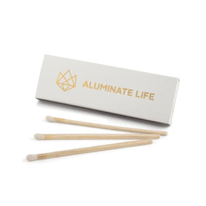 Box of matches with a gold Aluminate Life logo and three wooden matches with white tips, designed to complement the Energy Glass Candle | Aluminate Life for a stylish and functional lighting accessory.