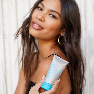 Smiling woman with glowing skin holding a tube of Acidophilus Probiotic Facial Cream | Epicuren Discovery, showcasing skincare for healthy, radiant complexion.