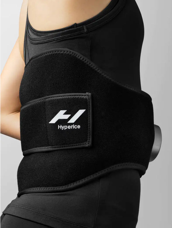 Person wearing a black recovery and compression wrap on their lower back with the logo visible on the strap, designed for enhanced wellness and support called Venom 2 Back | Hyperice